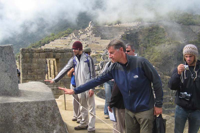 Tourists trying to feel the energy emitted by the Intihuatana in Machu Picchu