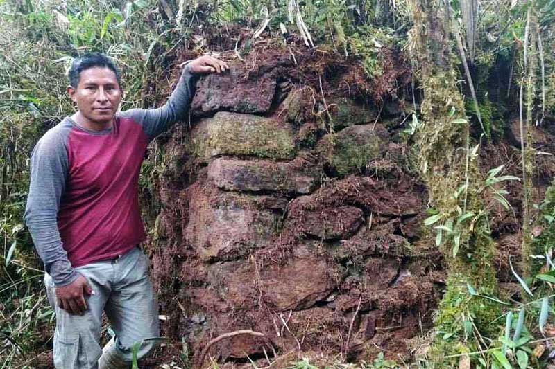 Poblador junto a muro de piedra descubierto