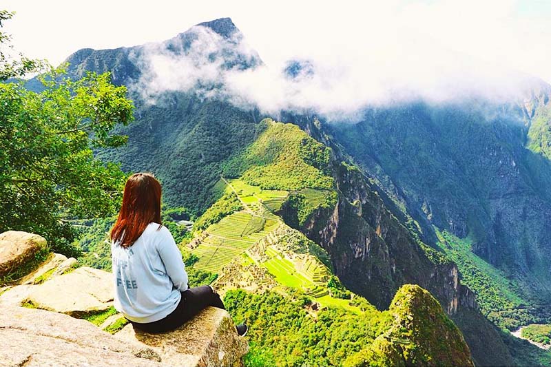 Tourist looking at Machu Picchu from the top of Huayna Picchu Mountain