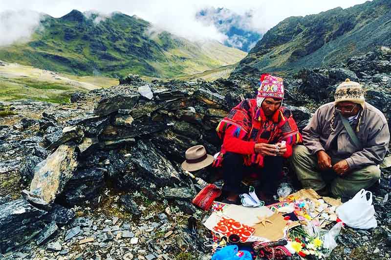 Sciamano che effettua un pagamento alla terra ai piedi di una montagna