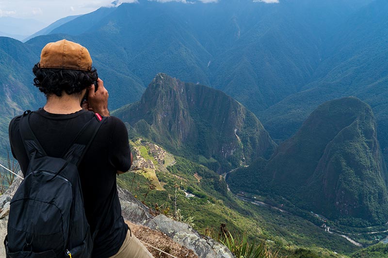 Visitante fotografiando desde la cima de la Montaña Machu Picchu