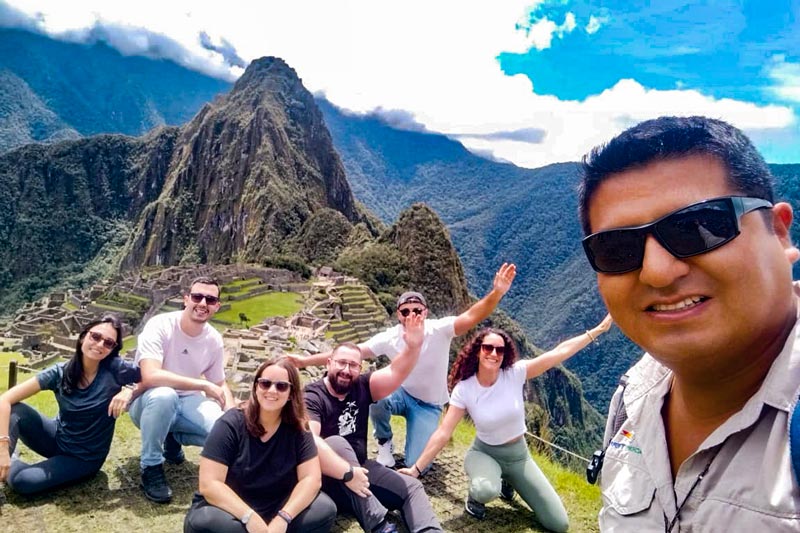 Guía tomándose foto con grupo de turistas en Machu Picchu