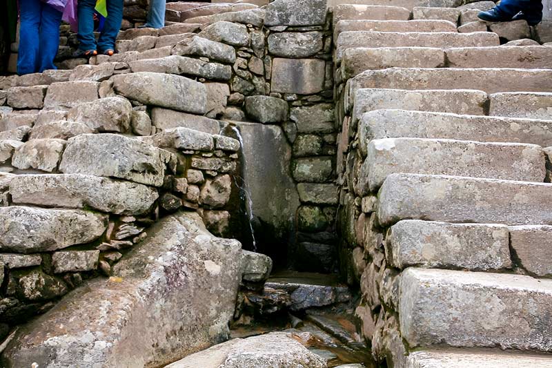 Fuente de agua debajo de las escalinatas de piedra en Machu Picchu