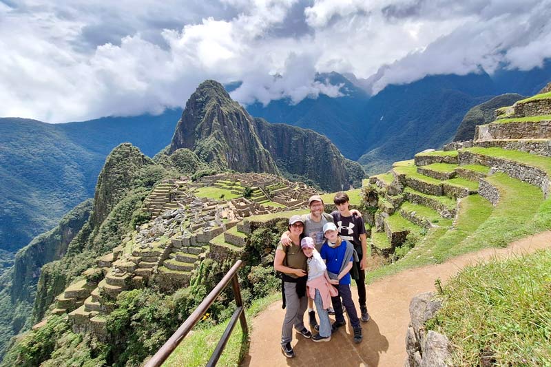 Foto de una familia de turistas con el fondo de Machu Picchu