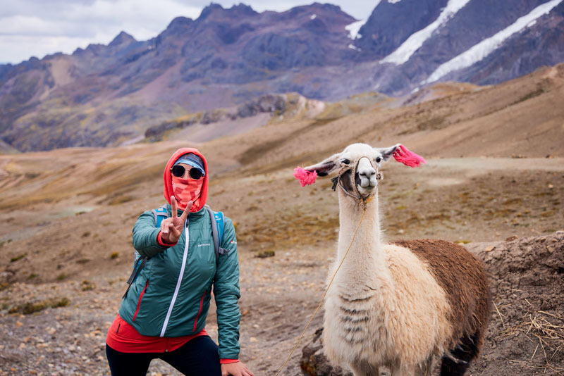 Photograph of a tourist and llama on the route to Rainbow Mountain