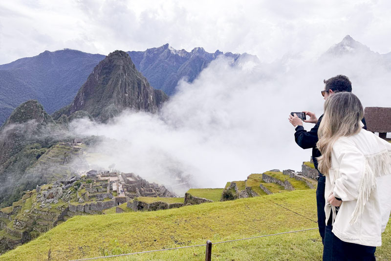 Casal de turistas fotografando Machu Picchu na neblina